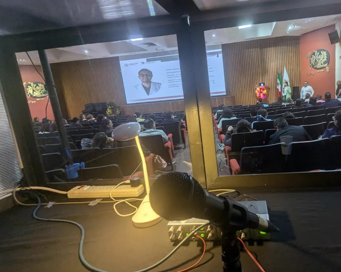 Cabina de interpretación con consola y micrófono durante un seminario médico